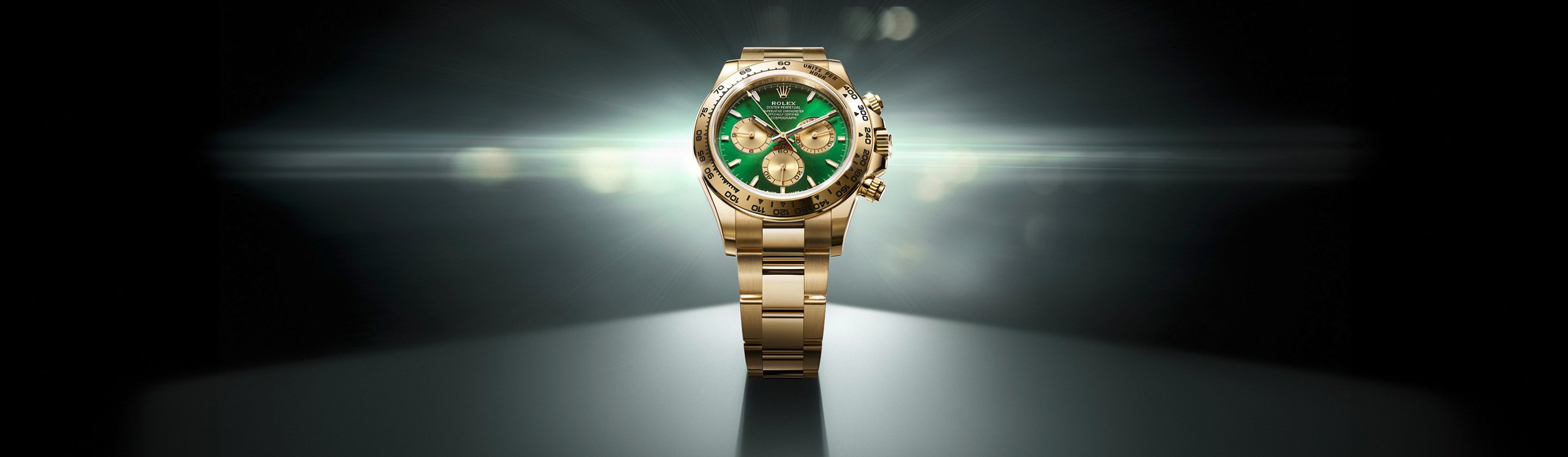 DAs Banner der Rolex Cosmograph Daytona Kollektion zeigt eine Uhr in Gold mit grünem Zifferblatt